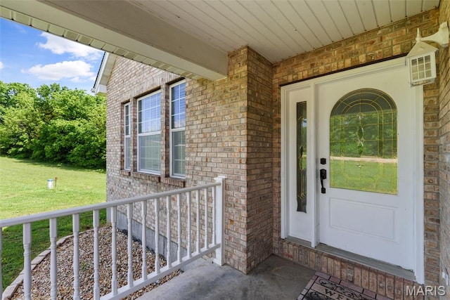 122 Morgan Lake Rd, De Soto, MO 63020 - view of exterior entry featuring brick siding, a yard, and a porch