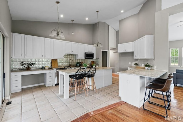 122 Morgan Lake Rd, De Soto, MO 63020 - kitchen with high vaulted ceiling, appliances with stainless steel finishes, backsplash, a breakfast bar area, and white cabinets