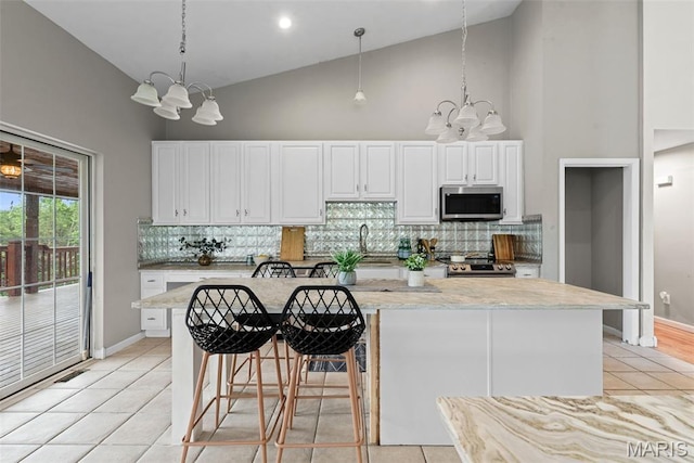 122 Morgan Lake Rd, De Soto, MO 63020 - kitchen featuring appliances with stainless steel finishes, a chandelier, high vaulted ceiling, light tile patterned floors, and tasteful backsplash