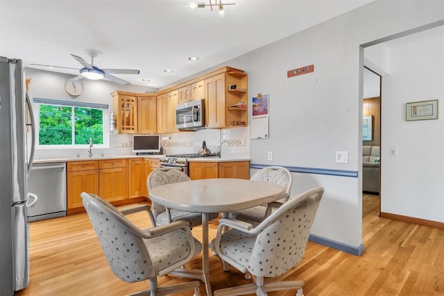 kitchen featuring stainless steel appliances, tasteful backsplash, a ceiling fan, light wood-type flooring, and light countertops