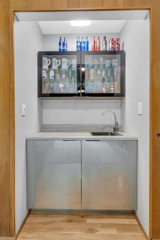 indoor wet bar featuring light wood-style floors and baseboards