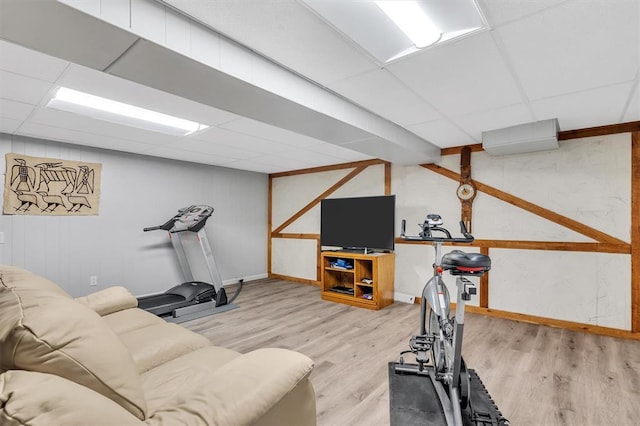 exercise area with a paneled ceiling, wood finished floors, and baseboards
