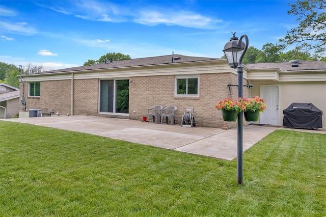 back of property featuring a patio area, central AC, a yard, and brick siding