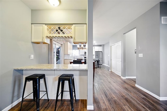 491 Cypress Creek Ln, Imperial, MO 63052 - kitchen featuring a peninsula, baseboards, dark wood-type flooring, a breakfast bar area, and decorative backsplash