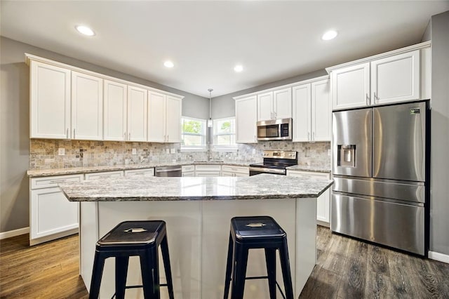 491 Cypress Creek Ln, Imperial, MO 63052 - kitchen with appliances with stainless steel finishes, dark wood-style floors, a sink, a kitchen breakfast bar, and white cabinetry
