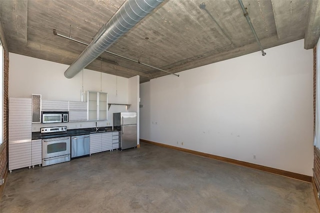 kitchen with appliances with stainless steel finishes, finished concrete floors, a sink, and baseboards