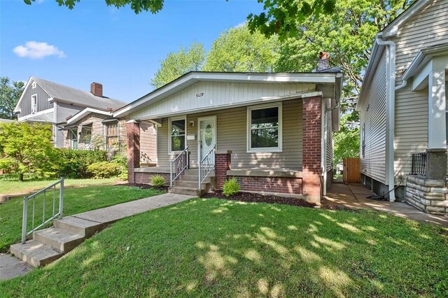 5039 Grace Ave, Saint Louis, MO 63116 - bungalow-style house with covered porch, brick siding, a front lawn, and a chimney