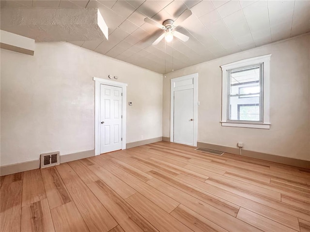 empty room featuring light wood-style floors, a ceiling fan, and baseboards