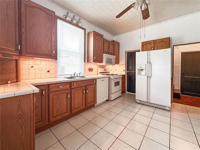 kitchen with white appliances, a sink, ceiling fan, decorative backsplash, and light tile patterned flooring