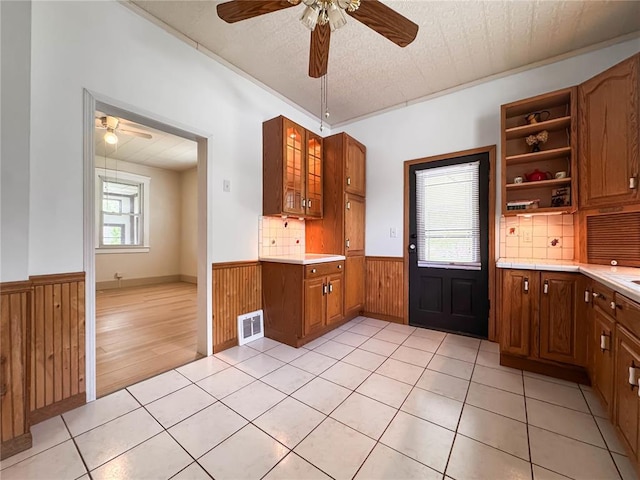 kitchen with a wainscoted wall, a ceiling fan, light countertops, open shelves, and wood walls