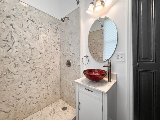 bathroom featuring tiled shower, vanity, and a chandelier