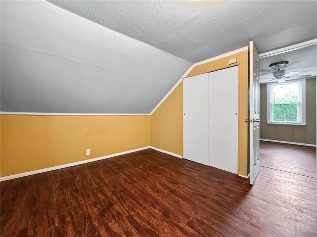 additional living space with lofted ceiling, wood finished floors, baseboards, ceiling fan, and a textured ceiling