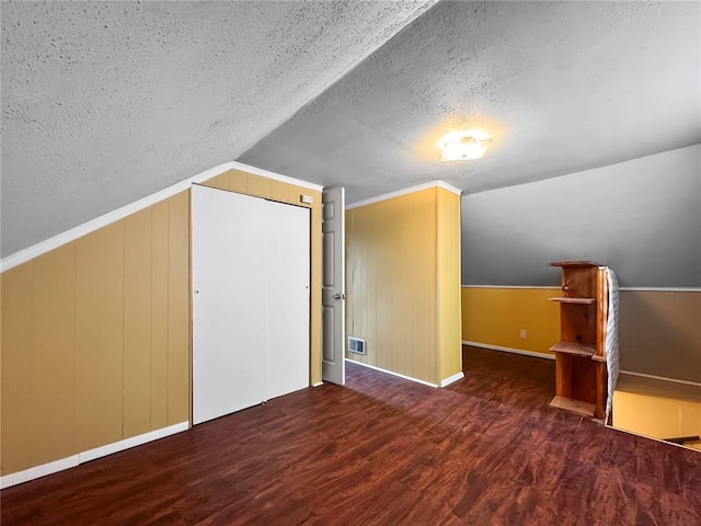 bonus room featuring a textured ceiling, wood finished floors, vaulted ceiling, and baseboards