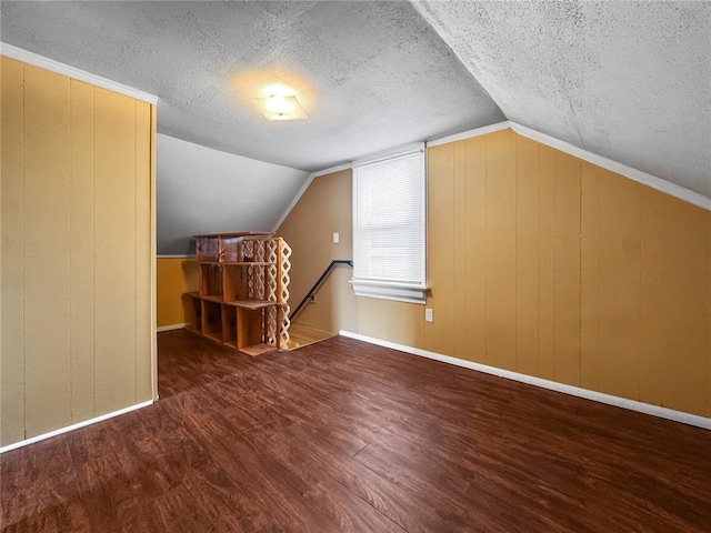 bonus room featuring wood finished floors, a textured ceiling, lofted ceiling, and baseboards
