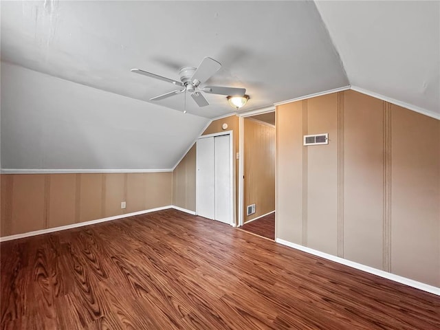 additional living space with lofted ceiling, a decorative wall, ceiling fan, wood finished floors, and baseboards