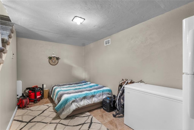 102 E Charlotte, Lilbourn, MO 63862 - bedroom featuring fridge, a textured ceiling, and tile patterned flooring