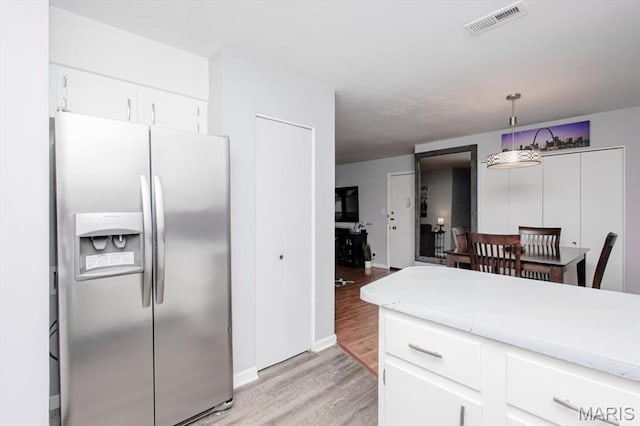 10077 N Bunker Hill Dr Unit F, Mehlville, MO 63123 - kitchen featuring stainless steel fridge, light wood-style flooring, light countertops, white cabinetry, and hanging light fixtures