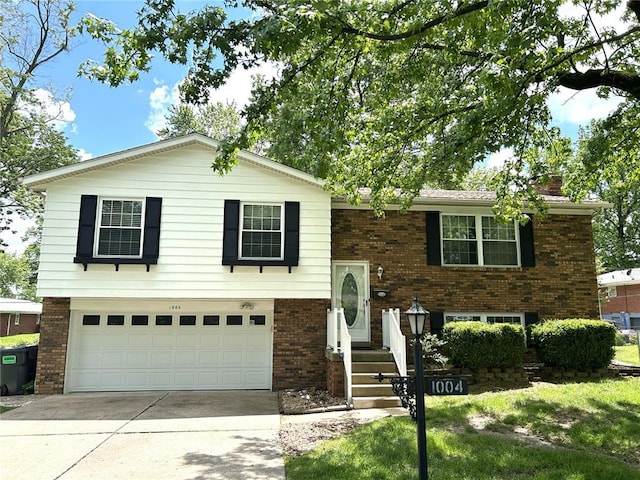raised ranch with brick siding, concrete driveway, an attached garage, and a chimney