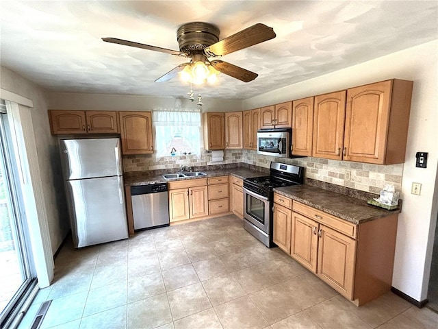 kitchen with appliances with stainless steel finishes, dark countertops, decorative backsplash, and a ceiling fan