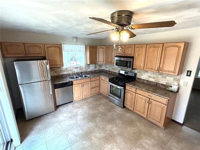 kitchen with stainless steel appliances, decorative backsplash, dark countertops, a sink, and light brown cabinets