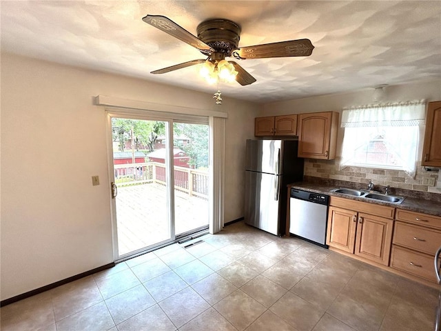kitchen with appliances with stainless steel finishes, dark countertops, healthy amount of natural light, and a sink