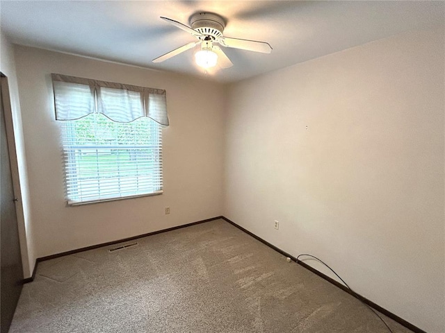 carpeted spare room with a ceiling fan and baseboards