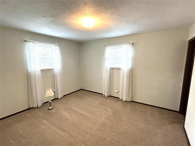 spare room with plenty of natural light, light colored carpet, and baseboards