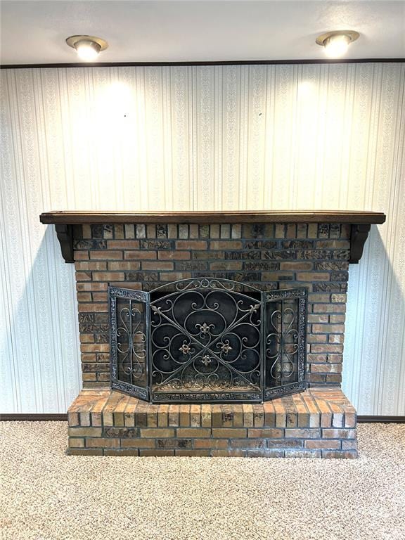 detailed view of a fireplace, wallpapered walls, carpet floors, and baseboards