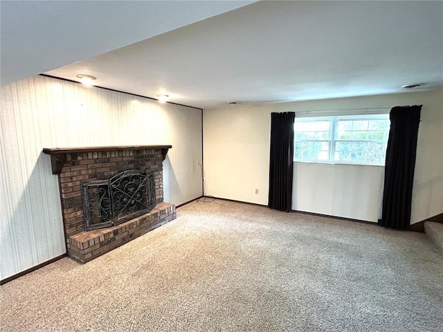 unfurnished living room featuring a fireplace, carpet, baseboards, and wooden walls