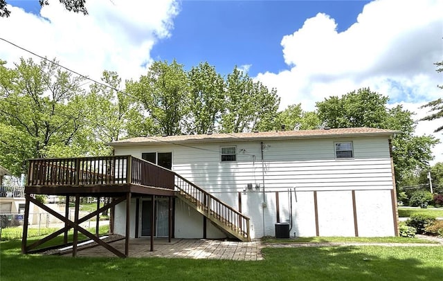 rear view of property featuring stairway, a deck, and a lawn