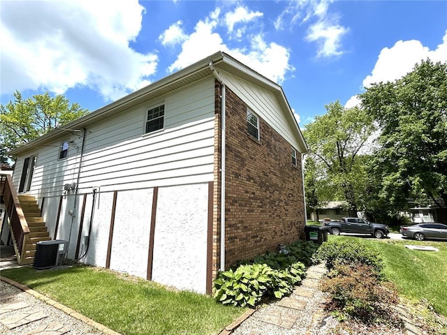 view of side of property featuring brick siding, central air condition unit, and stairs