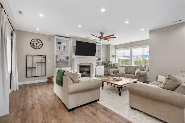 12930 Mohawk Dr, De Soto, MO 63020 - living room with a ceiling fan, light wood-style floors, a warm lit fireplace, recessed lighting, and baseboards