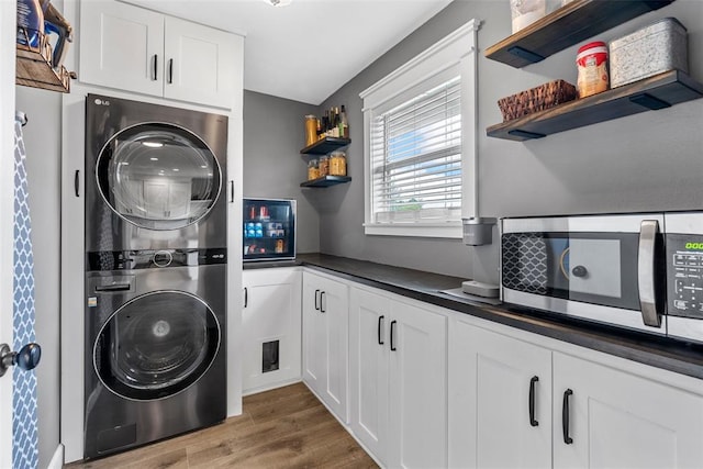 12930 Mohawk Dr, De Soto, MO 63020 - washroom featuring stacked washer / drying machine, wood finished floors, and cabinet space