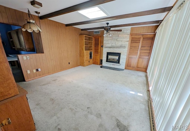 820 Lebanon Ave, Belleville, IL 62221 - unfurnished living room featuring wooden walls, beamed ceiling, a ceiling fan, a stone fireplace, and carpet