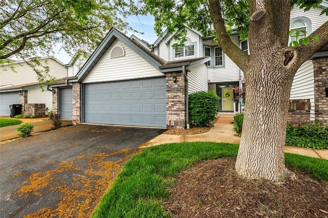 view of front of home with driveway, an attached garage, and brick siding