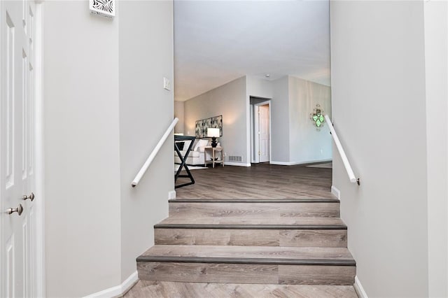 stairway with wood finished floors and baseboards