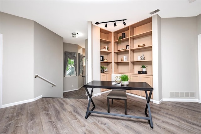 home office featuring track lighting, wood finished floors, and baseboards