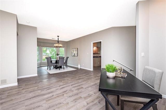 dining space featuring a chandelier, light wood finished floors, and baseboards