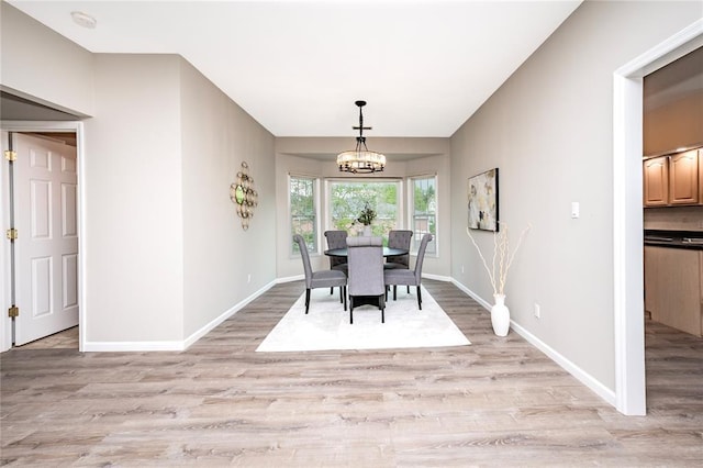 dining room with a chandelier, light wood-type flooring, and baseboards
