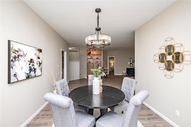 dining area with a chandelier, light wood finished floors, and baseboards