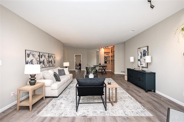 living area with baseboards and wood finished floors
