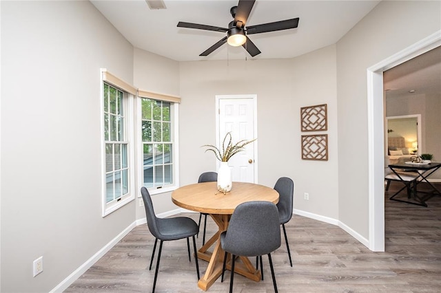 dining room with ceiling fan, light wood-style flooring, and baseboards
