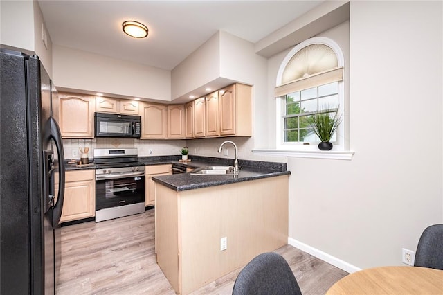kitchen featuring black appliances, a sink, a peninsula, and light brown cabinetry