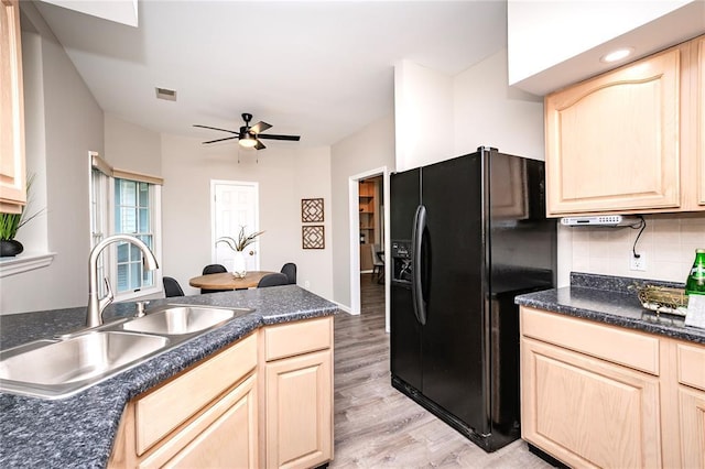 kitchen featuring black refrigerator with ice dispenser, a sink, light brown cabinets, light wood finished floors, and dark countertops