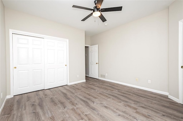 unfurnished bedroom with wood finished floors, baseboards, and a closet