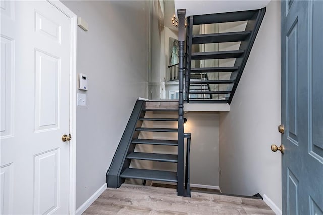 staircase featuring baseboards and wood finished floors