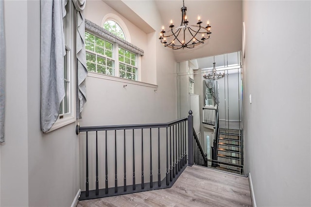 stairs with a chandelier, wood finished floors, and baseboards