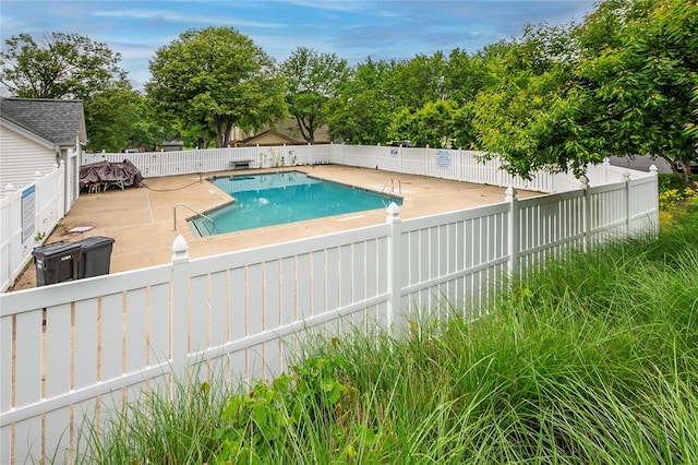 view of pool with a fenced backyard, a patio, and view of wooded area