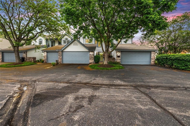 obstructed view of property featuring stone siding and a garage
