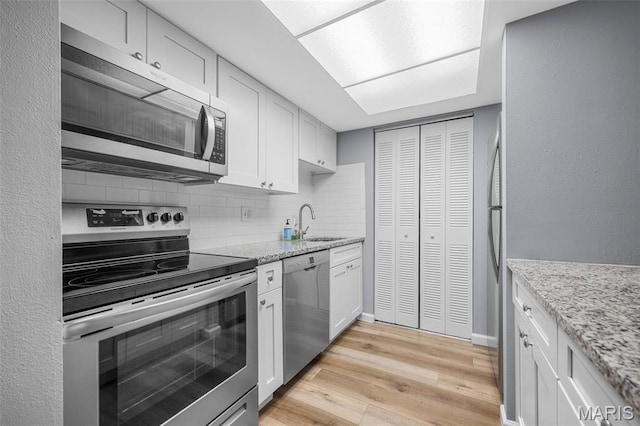11 Fairways Cir Unit A, Saint Charles, MO 63303 - kitchen with appliances with stainless steel finishes, a sink, tasteful backsplash, light wood-style flooring, and white cabinetry